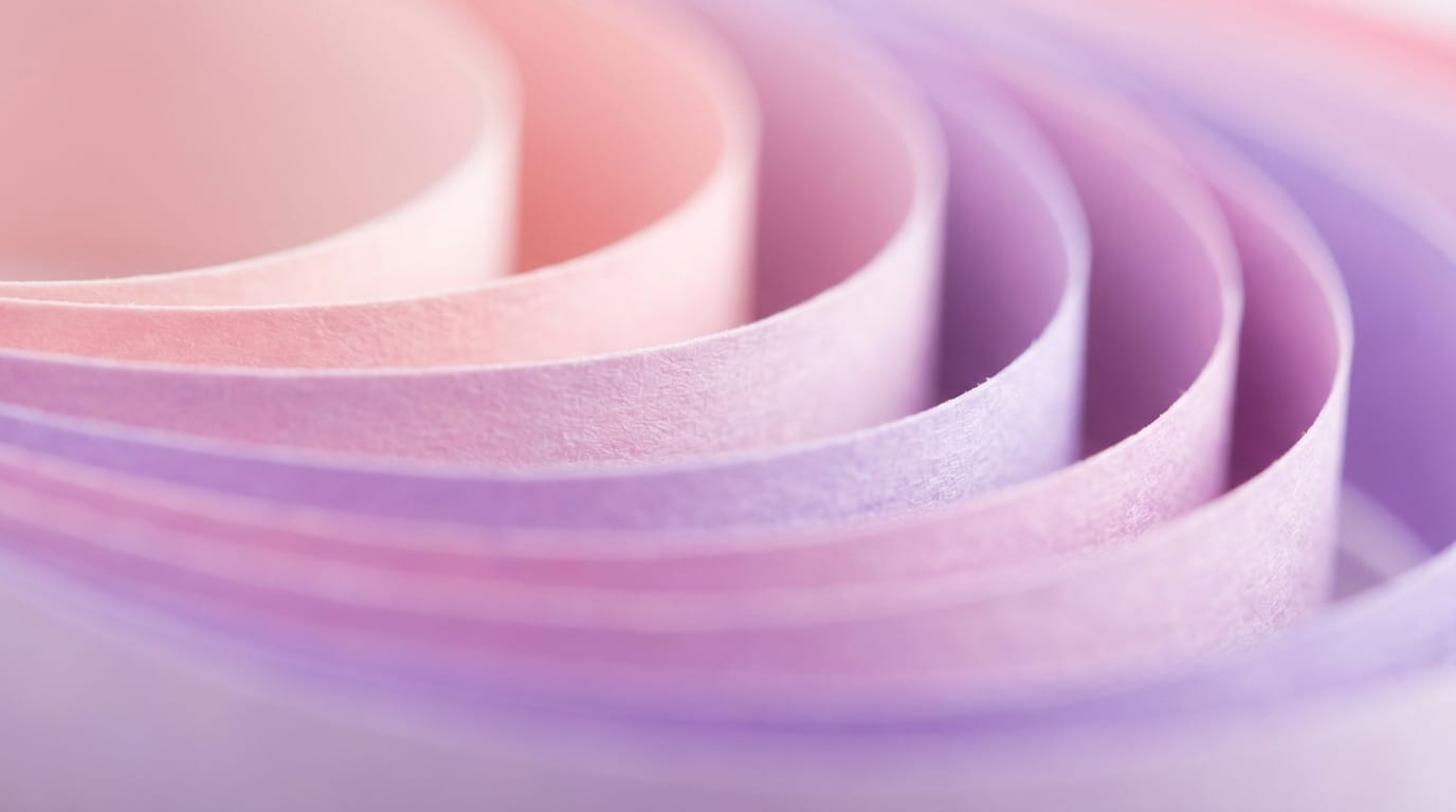 Macro photography of colorful paper layers with smooth curves, soft pastel gradients in pink and purple, shallow depth of field, soft studio lighting, creating a dreamy abstract background texture